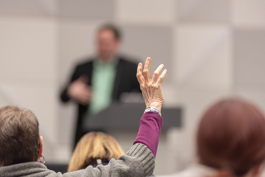 A woman raising her hand at a conference